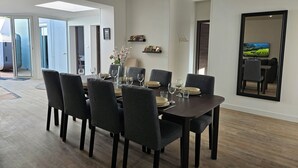 Een eetgedeelte met een donkerhouten tafel voor zes personen, omringd door grijze fauteuils.