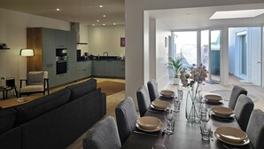 Een moderne woonkamer met een eetgedeelte, een keuken en uitzicht op het groen.