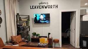 Una sala de estar moderna con un sofá, un televisor montado en la pared y un cartel que dice 'Welcome to Leavenworth'.