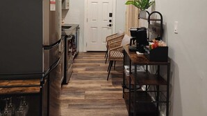 Una cocina estrecha con refrigerador, horno y un comedor con una silla y una mesa.