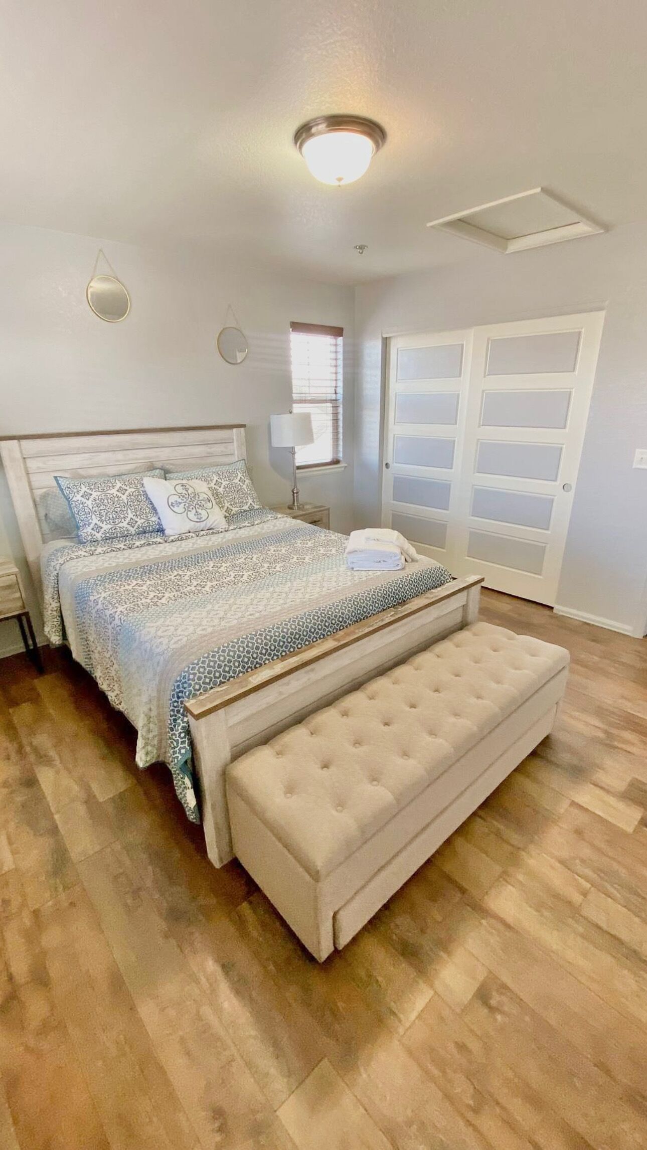 A bedroom with a large bed, a bench, a window, and a door.