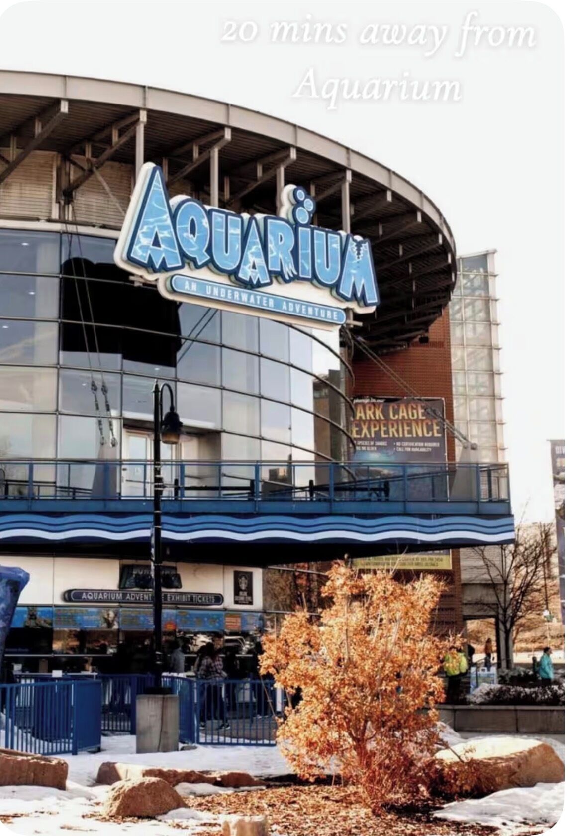 An aquarium with a large sign, a ticket booth, and a walkway.