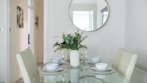 Une table à manger avec des chaises blanches, un plateau en verre et un vase rempli de fleurs.