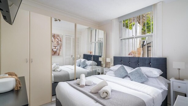 Une chambre moderne avec deux lits, un grand miroir et une vue sur la verdure environnante.