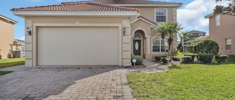 A single-story house with a beige garage door, a tiled roof, and a well-maintained lawn.