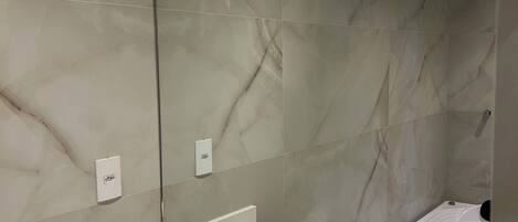 A modern bathroom with a large mirror, a bathtub, and a vanity with toiletries.