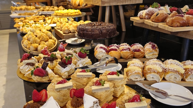 Un bufé con diversos pasteles y postres, incluyendo pasteles y repostería con fresas y chocolate.
