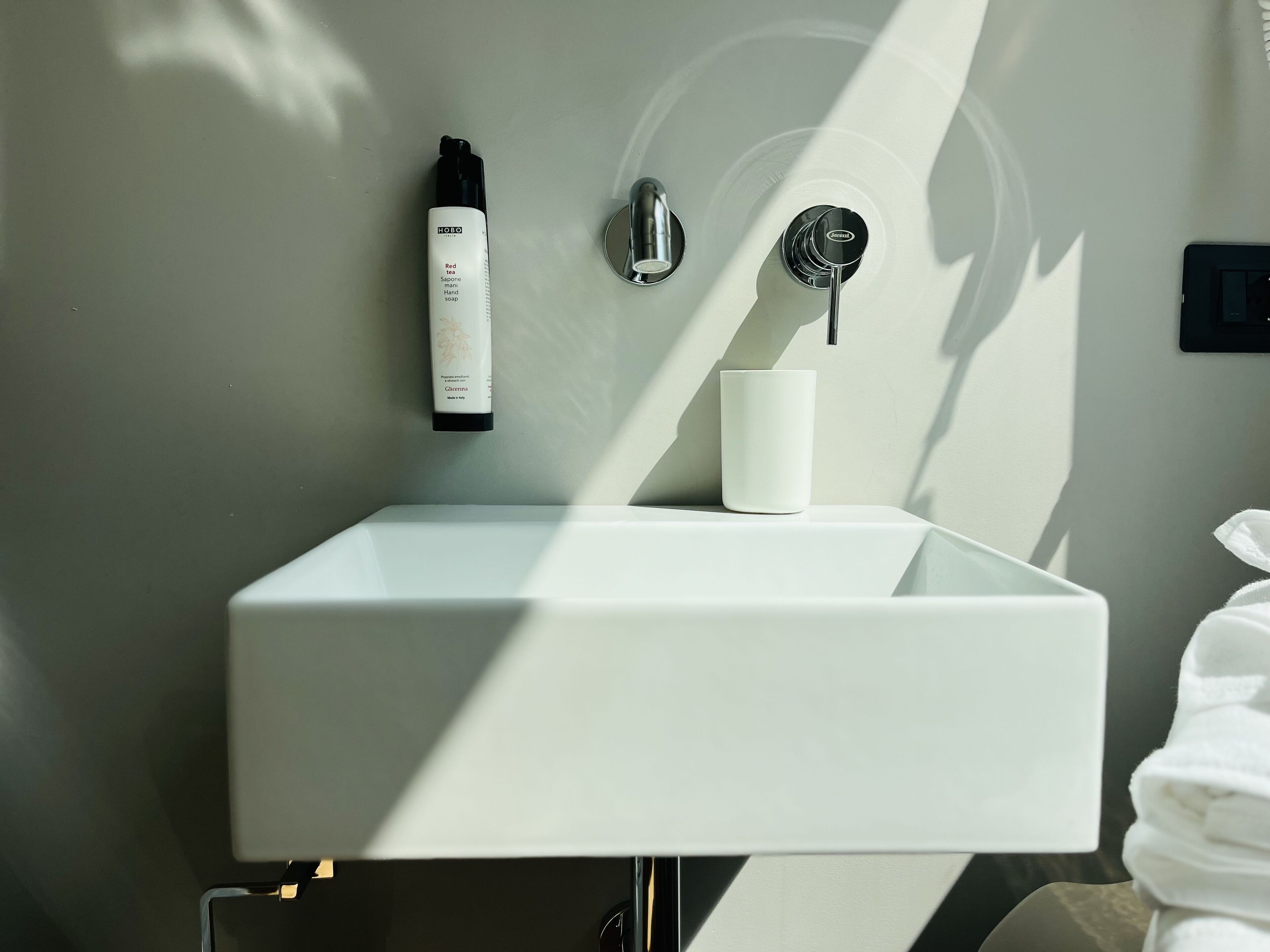 Ein modernes Badezimmer mit einem weißen Waschbecken, einer Seife und einem Wasserhahn.