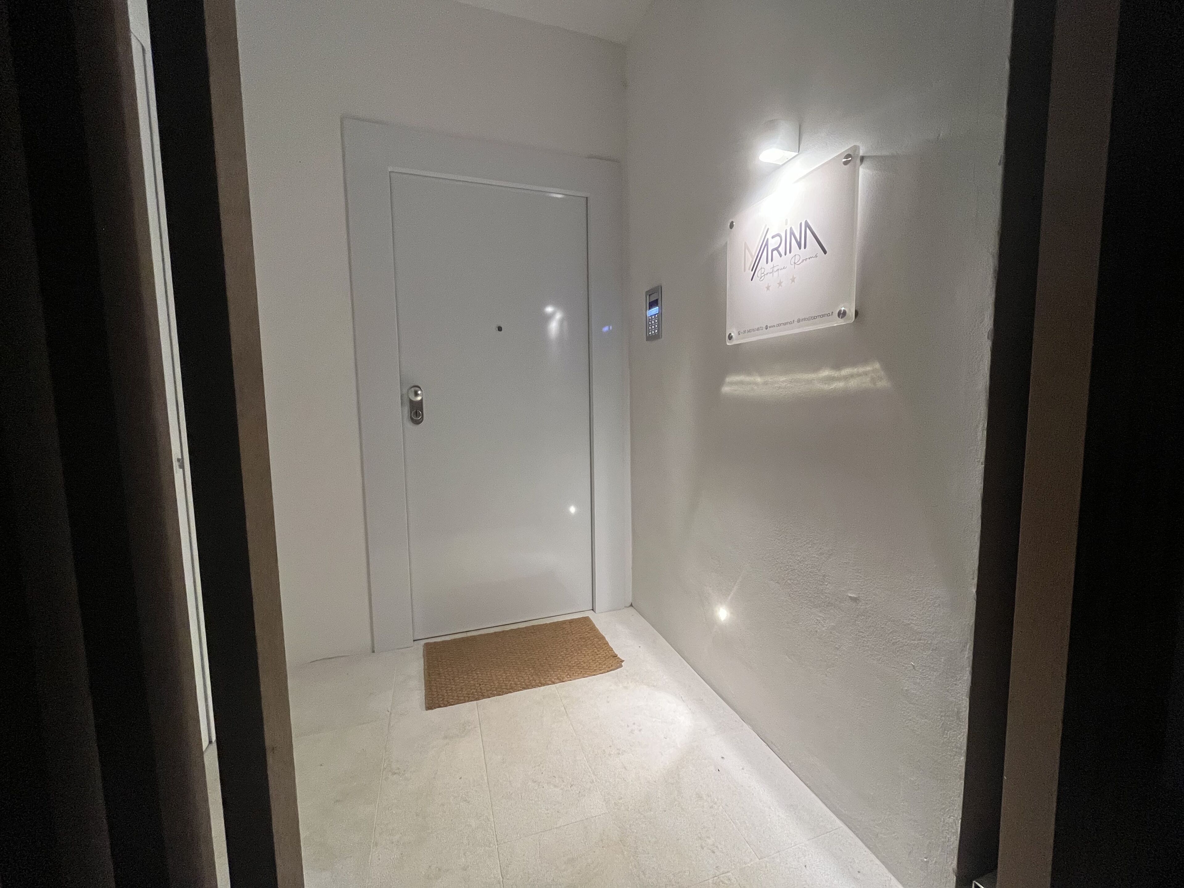A narrow hallway with a door, a small rug, and a sign on the wall.