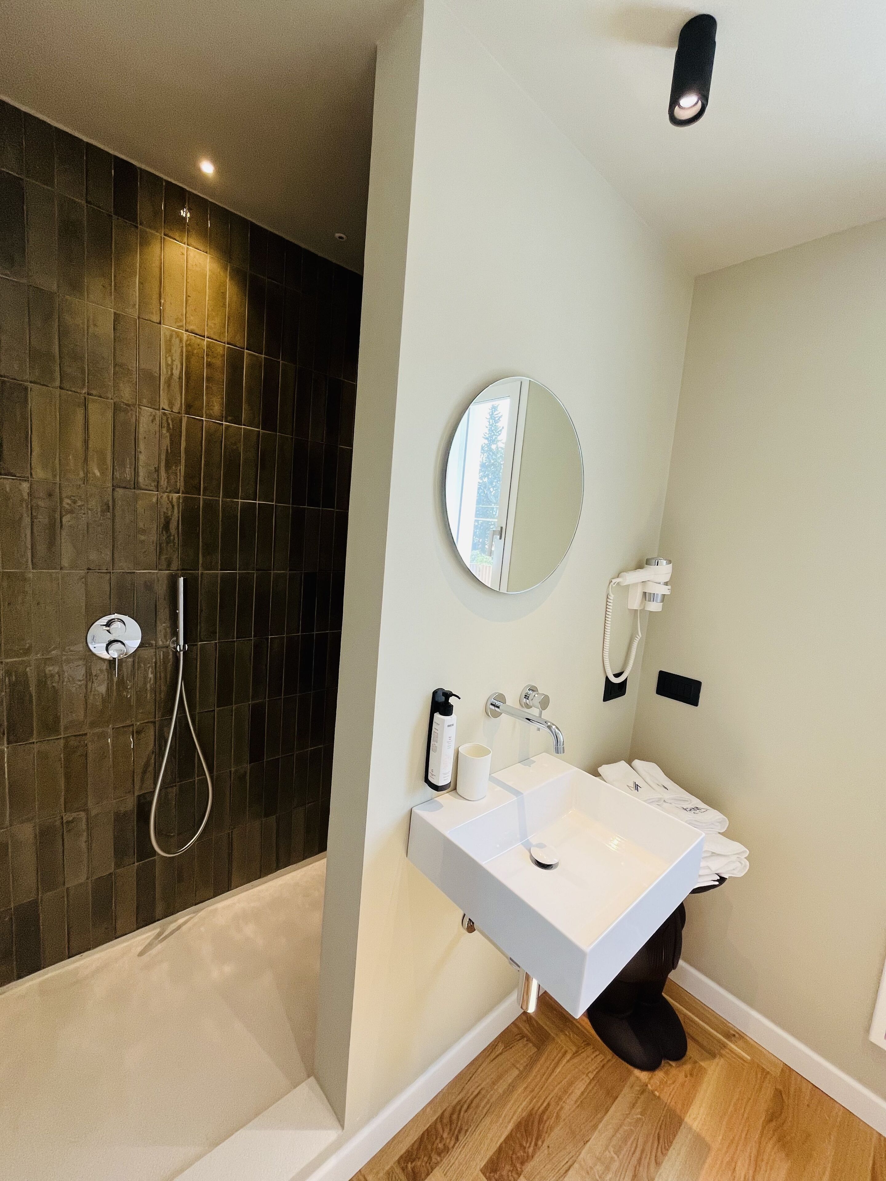 A modern bathroom with a shower, a sink, a mirror, and a towel rack.