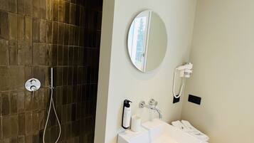 A modern bathroom with a shower, a sink, a mirror, and a towel rack.