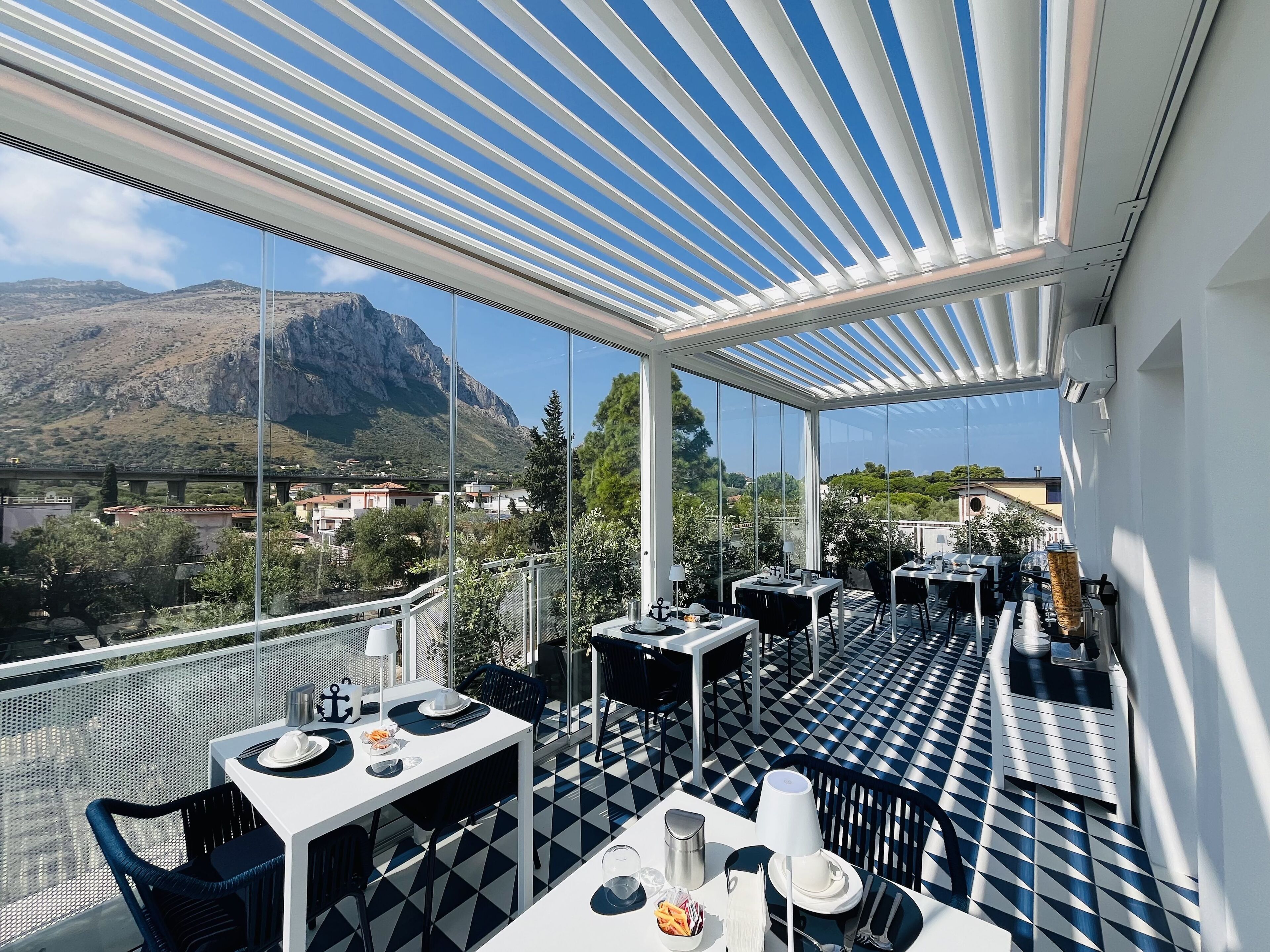 Une terrasse avec des tables et des chaises, une vue sur une montagne et un pont en arrière-plan.