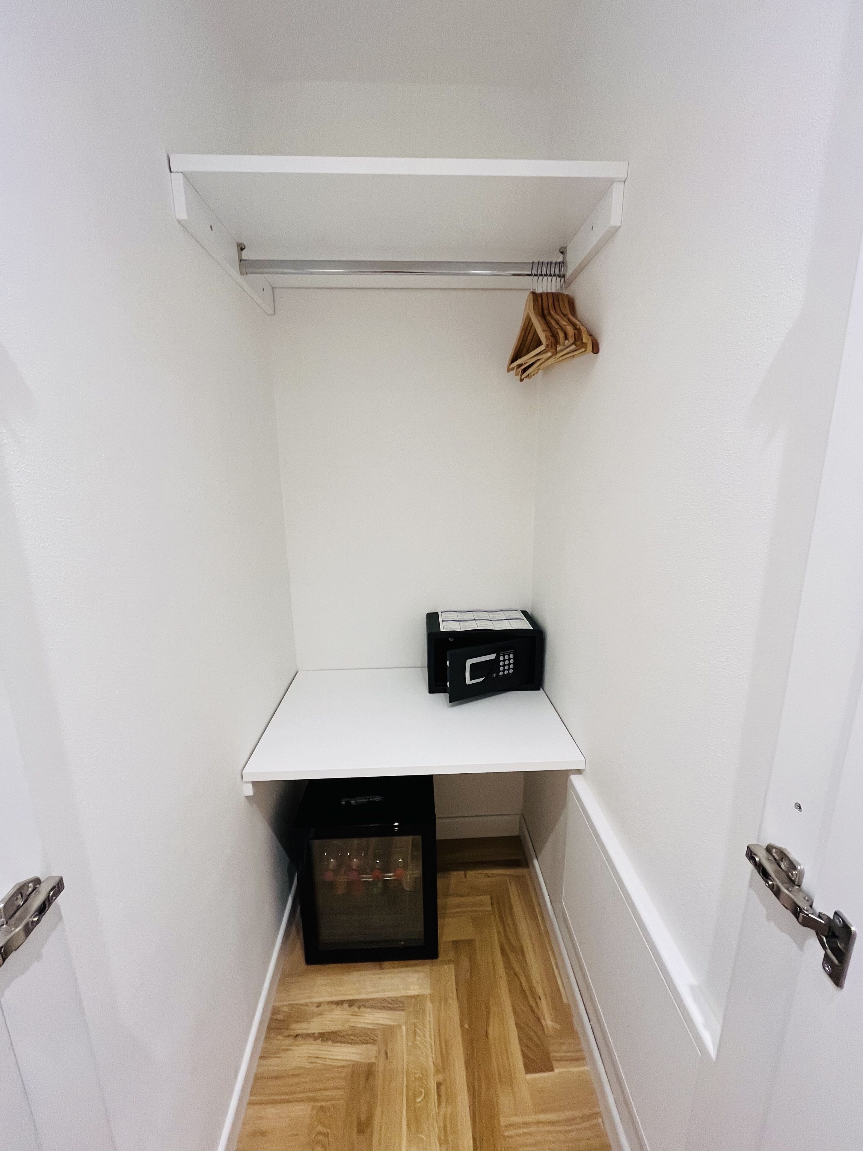 Een kleine kamer met een wit schap, een magnetron en een klein zwart apparaat op de vloer.