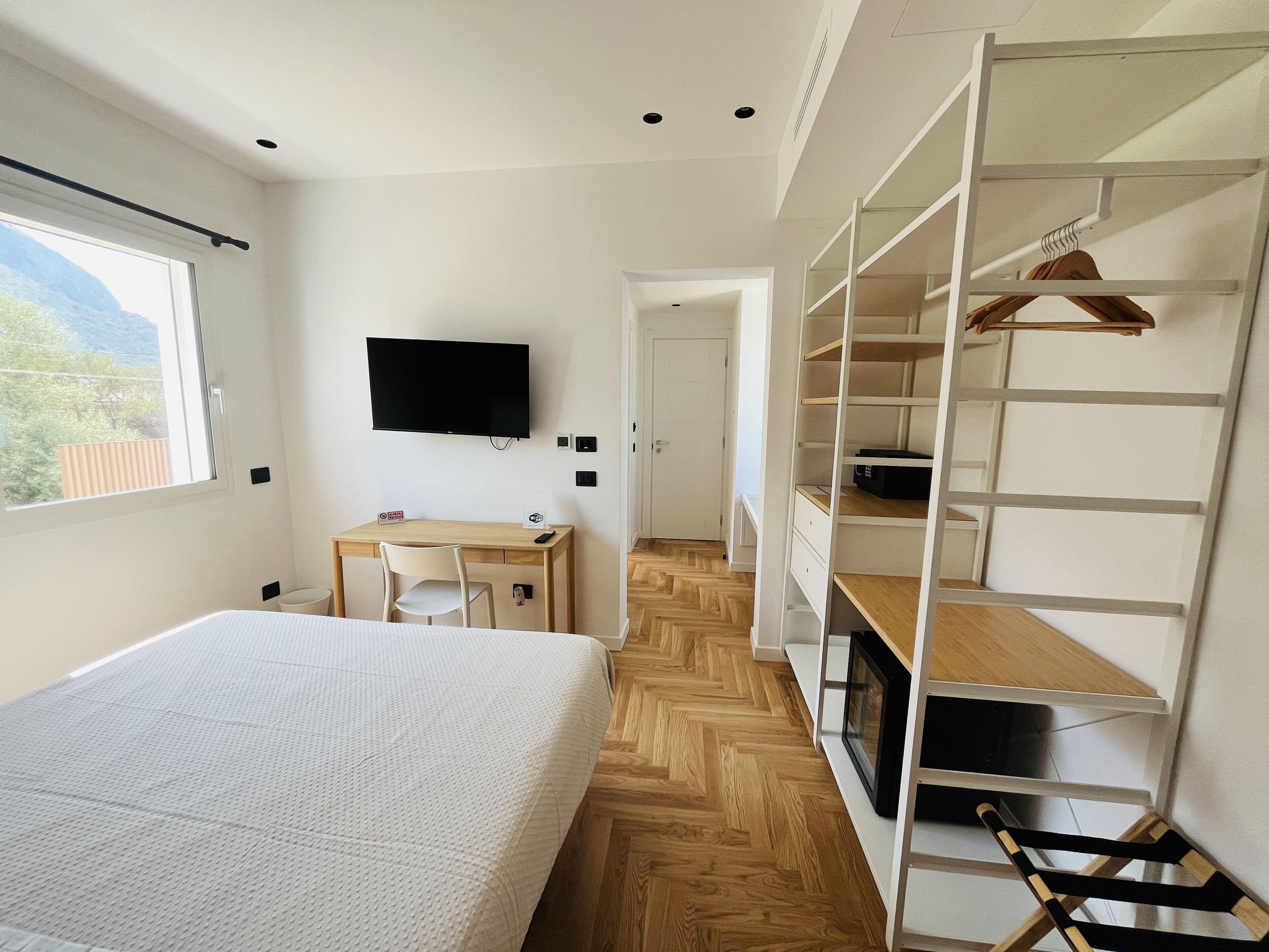 Een slaapkamer met een bed, een bureau, een televisie en een kledingkast.