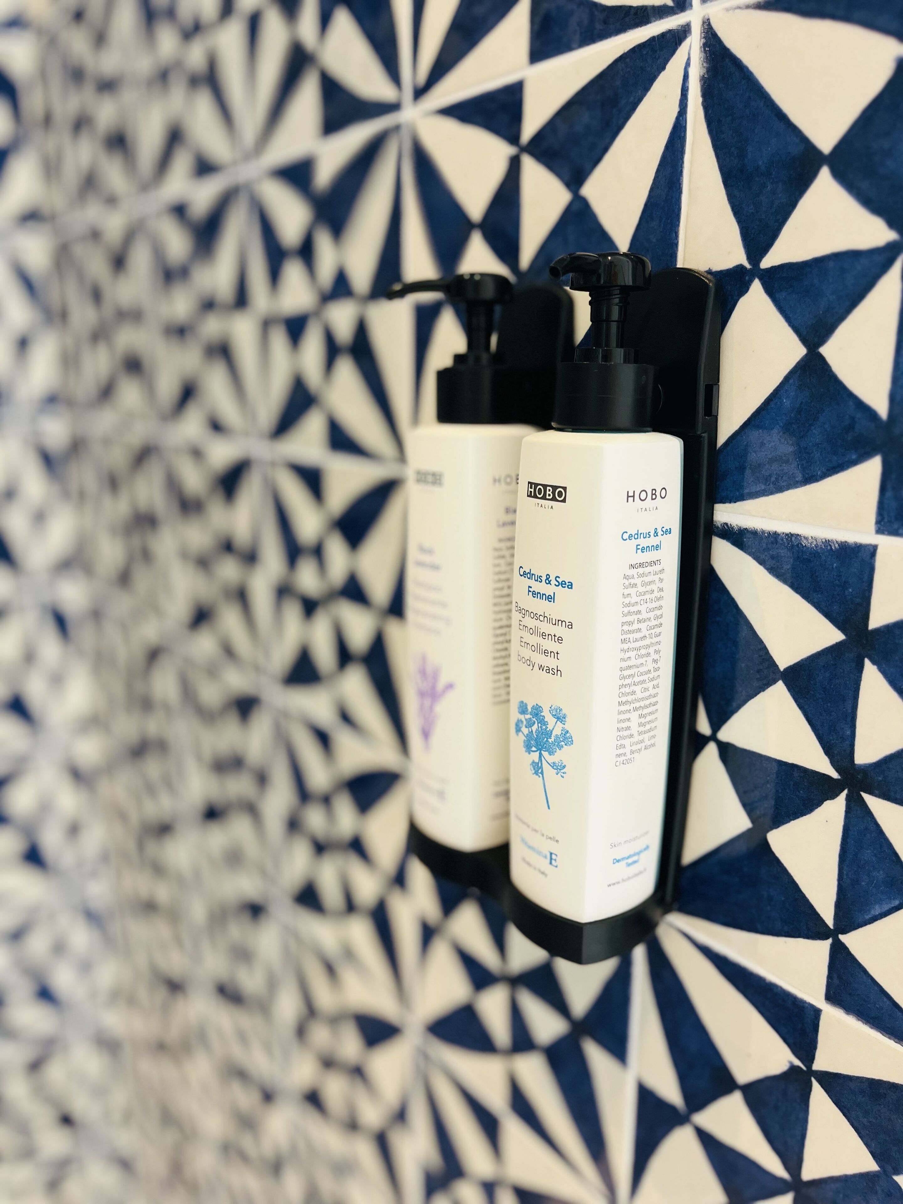 Three bottles of body wash against a patterned tile wall.