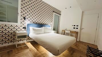 Un dormitorio moderno con pared de diseño geométrico, una cama grande, un escritorio y una silla.