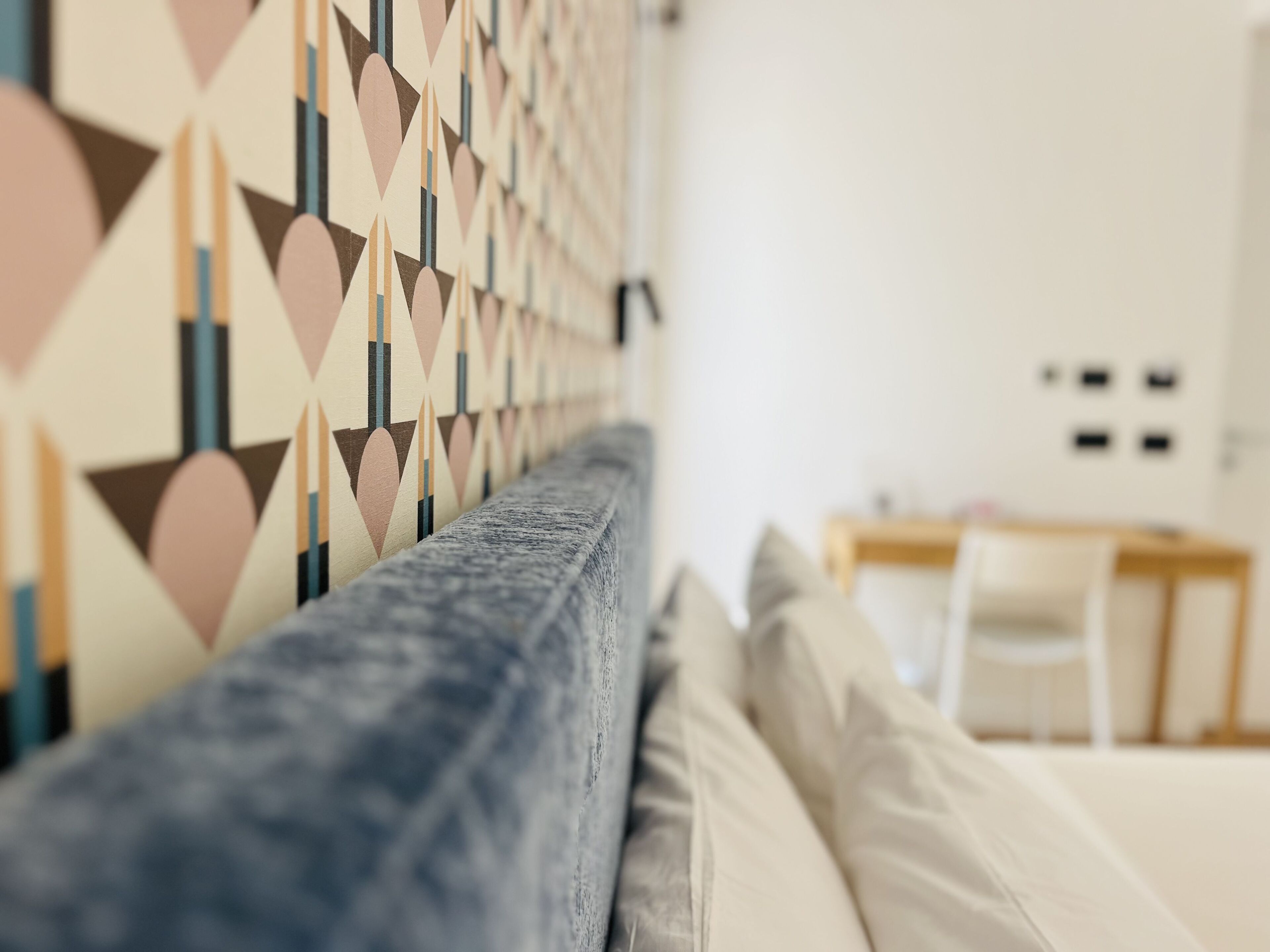 Una sala moderna con una pared con diseño, un sofá y un comedor al fondo.