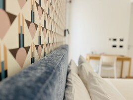 Una sala moderna con una pared con diseño, un sofá y un comedor al fondo.