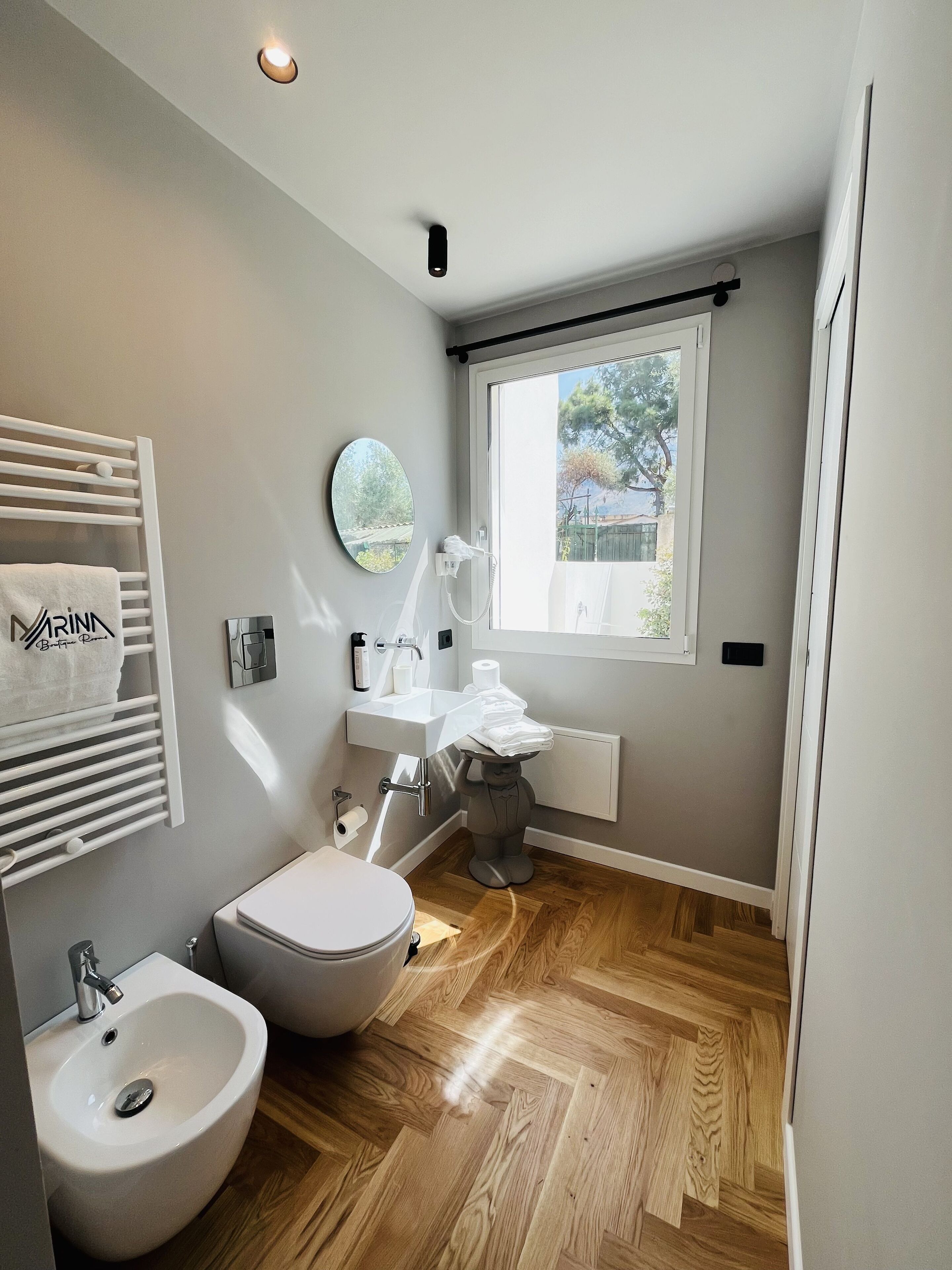 A modern bathroom with a toilet, bidet, sink, and a mirror.