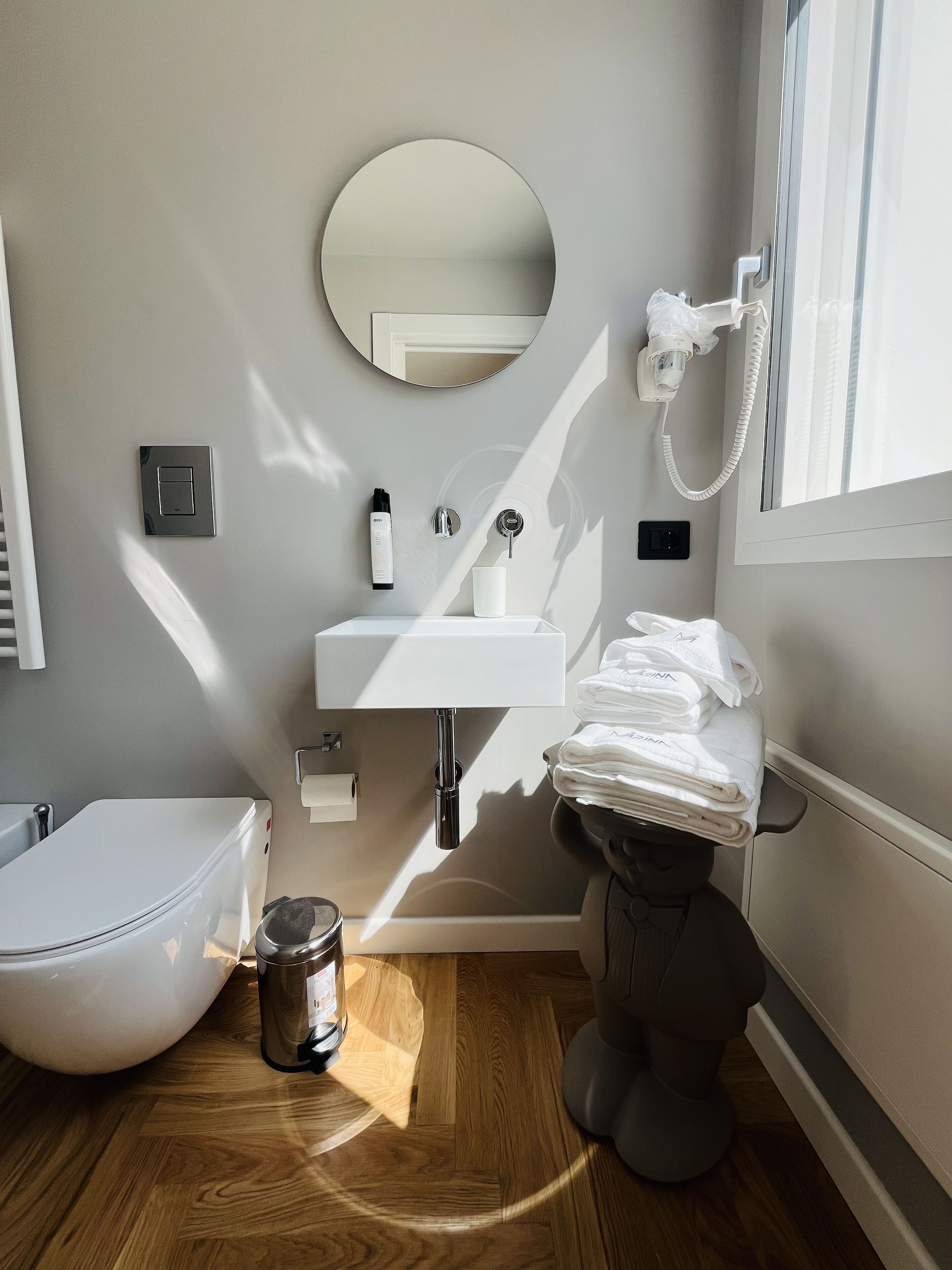 A modern bathroom with a toilet, bidet, sink, and a mirror.