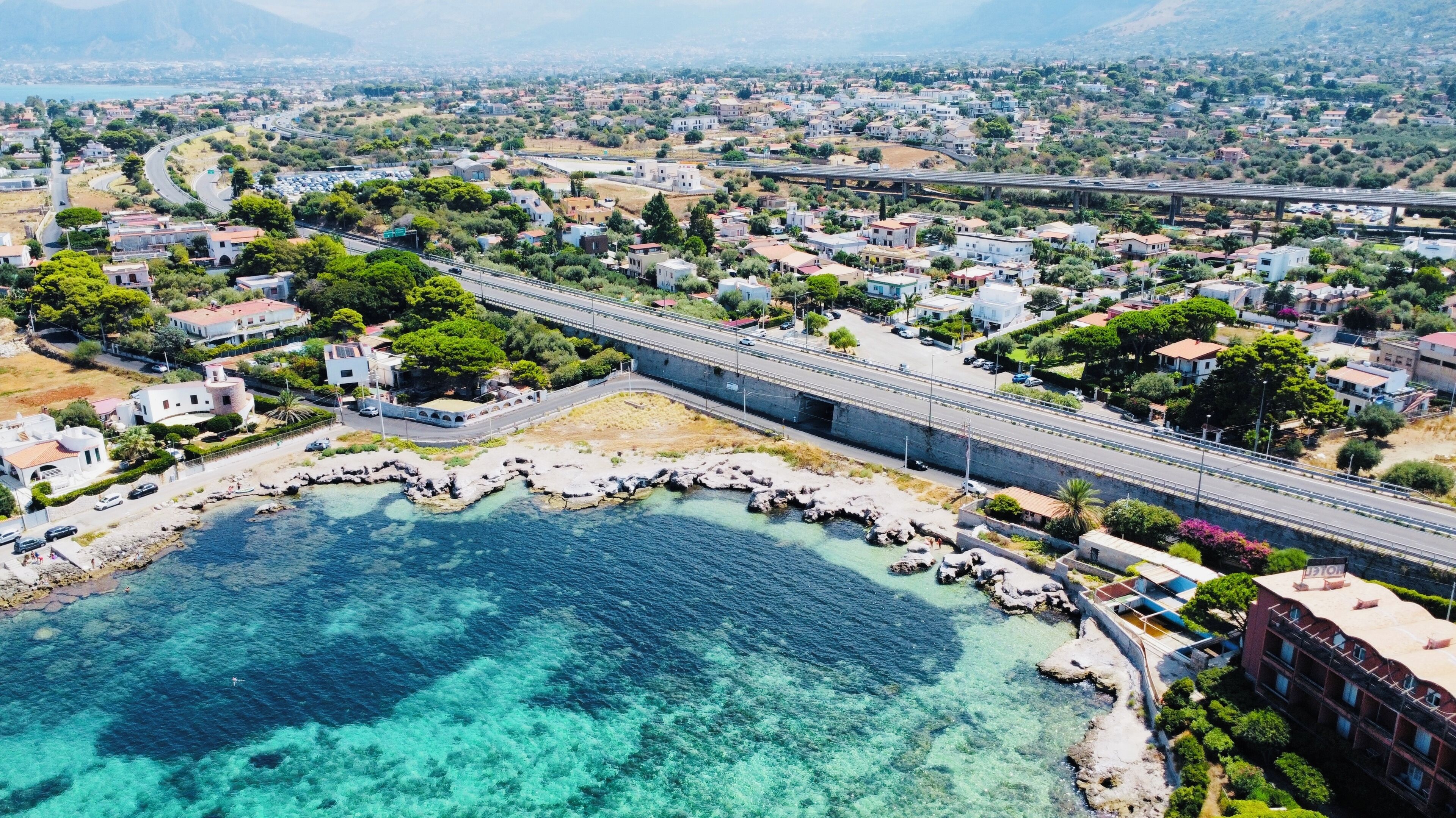 Eine Küstenstadt mit einer Brücke, klarem, blauem Wasser und Wohngebäuden.