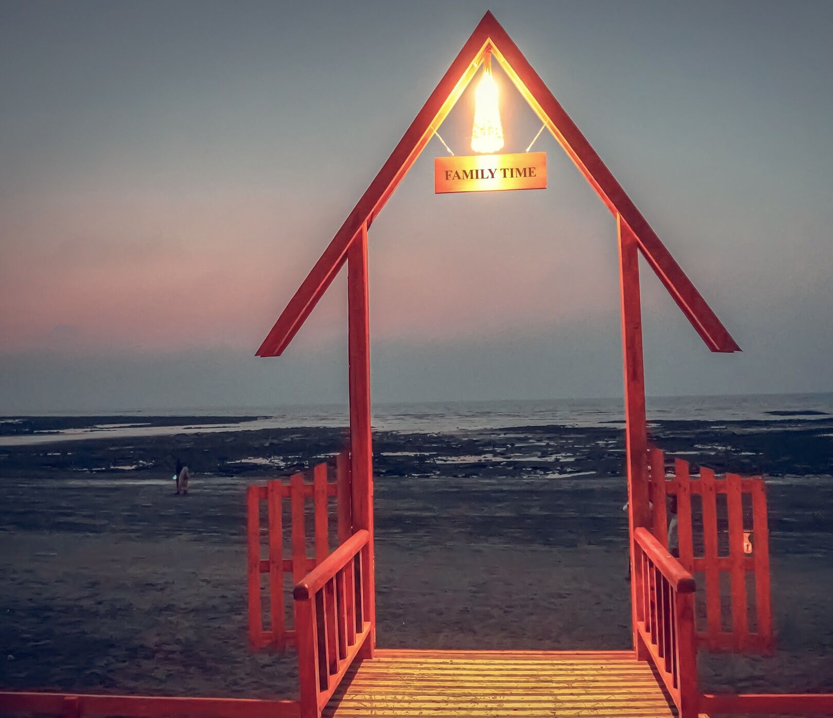 A wooden beach structure with a sign reading "FAMILY TIME" and a view of the ocean.
