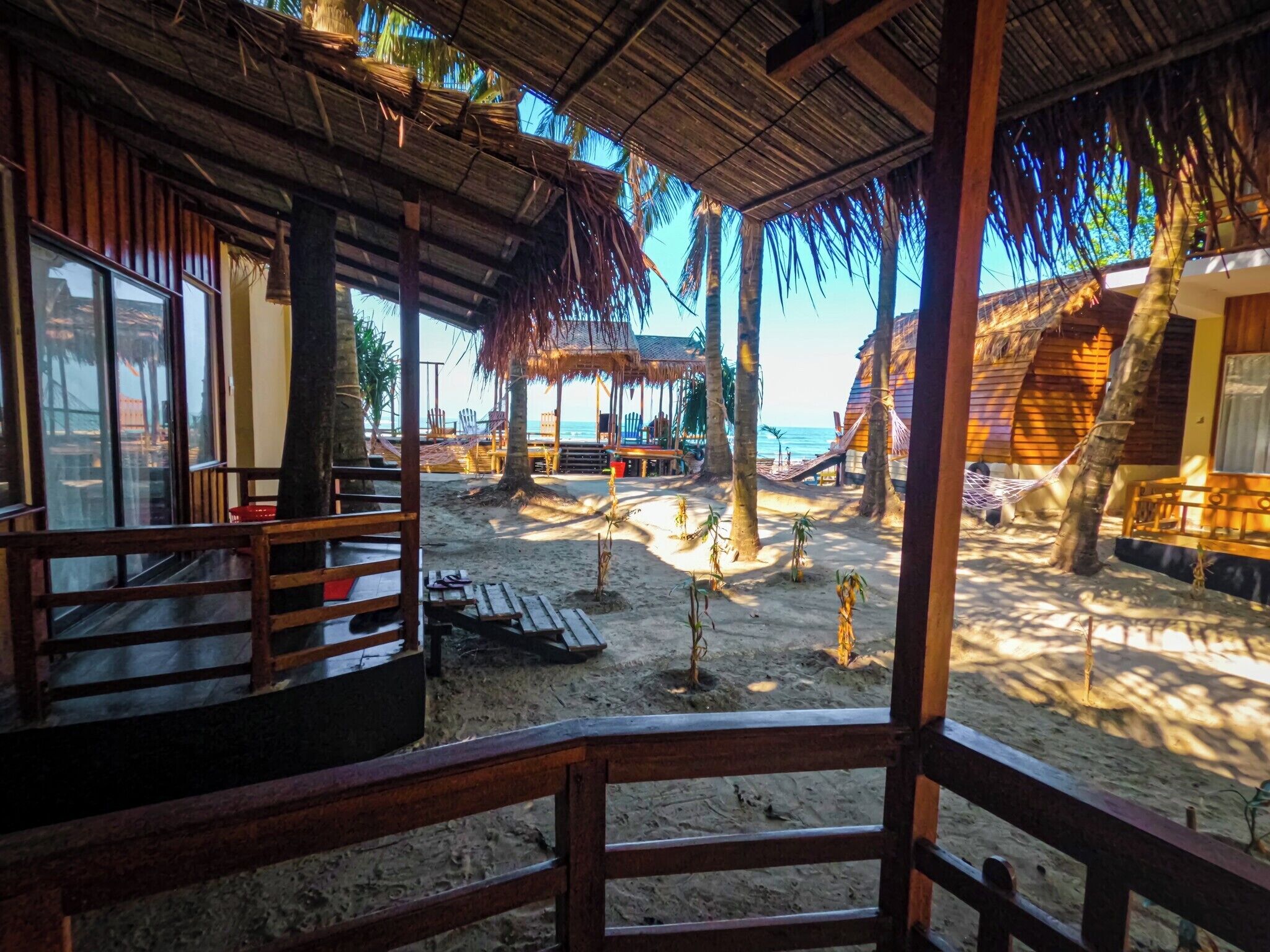A beachside resort with wooden cabins, thatched-roof structures, and a sandy beach.
