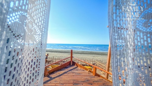 Une promenade en bois qui mène à une plage d’où l’on a une vue dégagée sur l’océan.