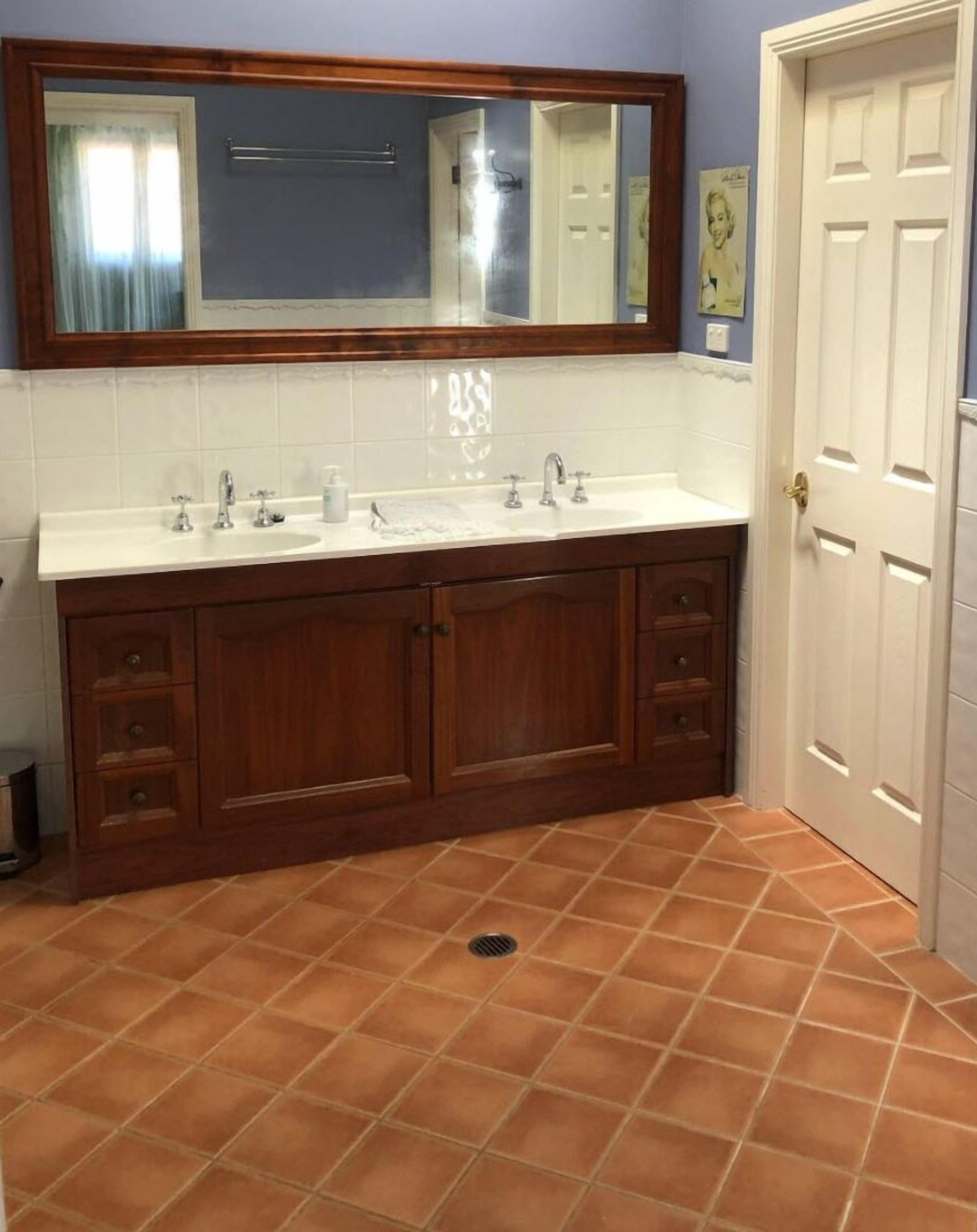 A bathroom with a double vanity, a large mirror, and a tiled floor.