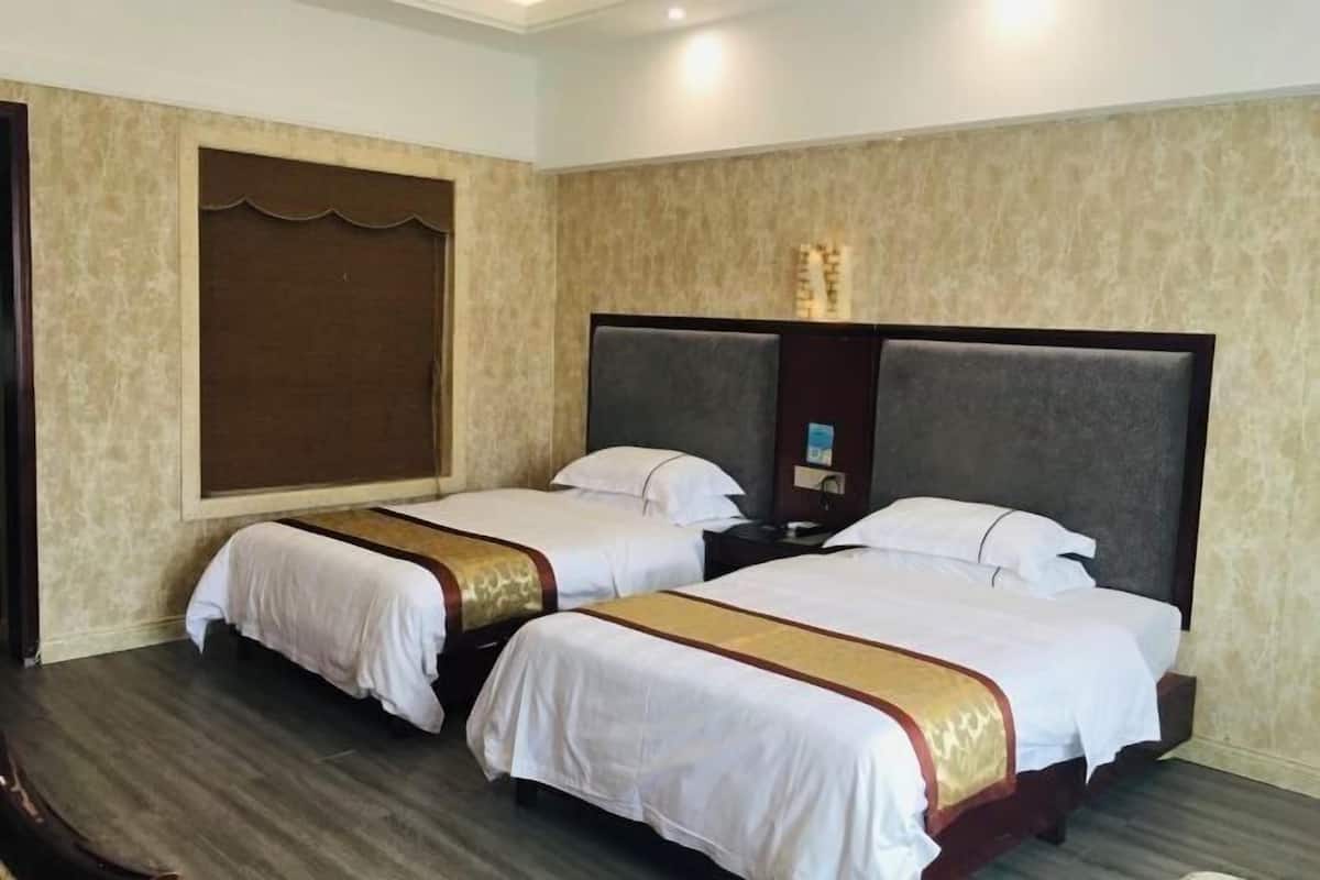 Une chambre d’hôtel avec deux lits, une grande fenêtre avec un rideau et un plancher en bois.