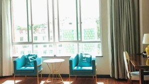 A room with two blue sofas, a small round table, and a large window with curtains.