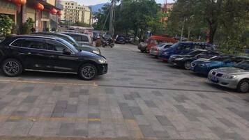 Ein Parkplatz mit mehreren parkenden Autos, ein Gebäude mit roten Laternen und Bäume im Hintergrund.