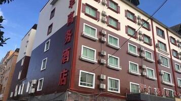 Een hotel met meerdere verdiepingen, een rood-witte gevel, veel ramen en airconditioningsapparaten.
