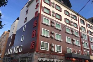 A multi-story hotel with a red and white facade, multiple windows, and air conditioning units. - Qiongzhong Runfeng Business Hotel (Qiongzhong)