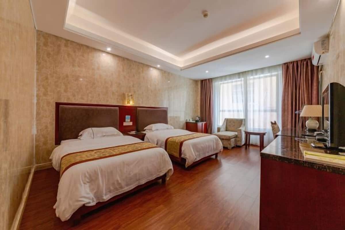 Une chambre d’hôtel avec deux lits, un petit coin salon, une télévision et un minibar.