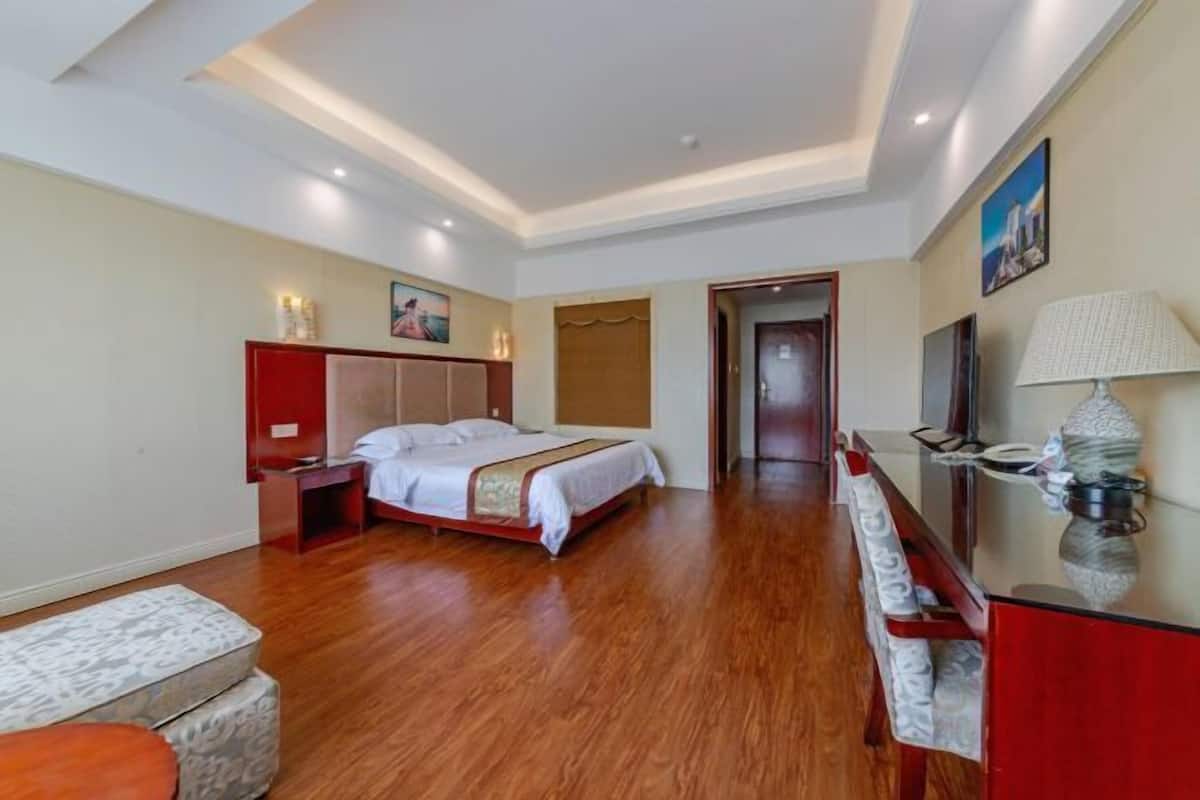 Une chambre d’hôtel avec un lit, une table de chevet, une lampe et une vue sur le couloir.