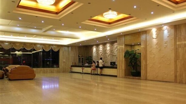 A spacious lobby with a polished marble floor, a reception desk, and a large potted plant.