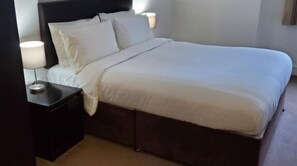 A neatly made bed with white linens in a hotel room. - 2 Bedroom Apartment in Canary Wharf London (London)