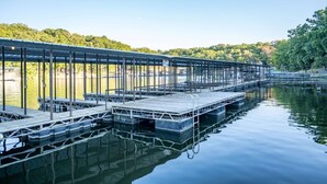 Un muelle largo y techado que se adentra en aguas tranquilas, con barandilla de metal y bancos a lo largo de su extensión.