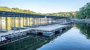 Une longue jetée couverte s’étendant dans une étendue d’eau calme, dotée d’une rambarde en métal et de bancs disposés le long de sa longueur.