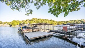 Eine Anlegestelle mit einer Holzplattform und Metallkonstruktionen, umgeben von ruhigem Wasser und Bäumen.
