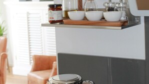 A kitchen with a coffee maker, shelves with glass jars, and a lamp. - Premium vacation apartment Alter Sandweg incl. beach chair  (Scharbeutz)