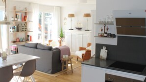 A modern kitchen with a built-in oven and a dining area with a white table and chairs. - Premium vacation apartment Alter Sandweg incl. beach chair  (Scharbeutz)
