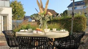 An outdoor dining area with a round table, black wicker chairs, and a clear view of the surrounding neighborhood. - Premium vacation apartment Alter Sandweg incl. beach chair  (Scharbeutz)