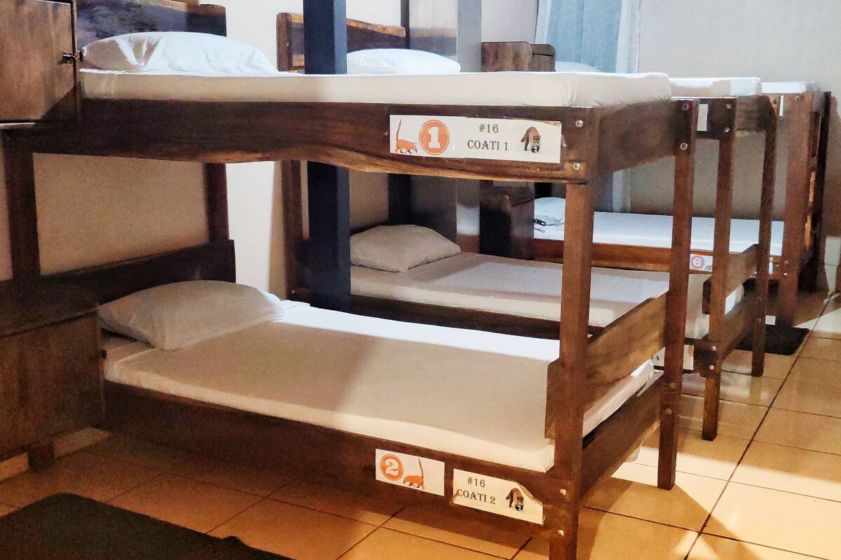 Camas literas con etiquetas individuales, un colchón oscuro y suelo de baldosas.