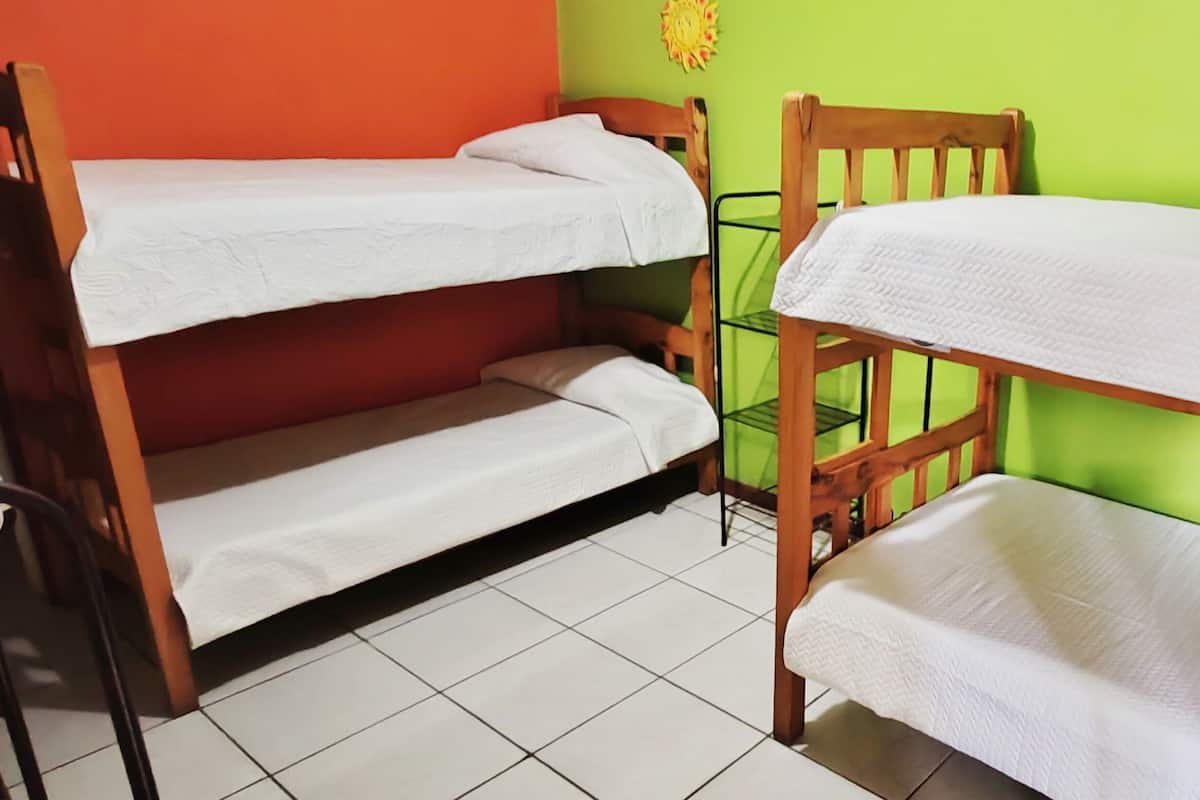 Una habitación con dos literas, una silla y una mesita.