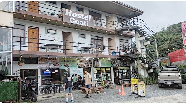 A hostel with a sign reading "Hostel Coati" and a nearby "La Suda Coati" restaurant. - Hostel Coati Place Bed & Breakfast  (Monteverde)