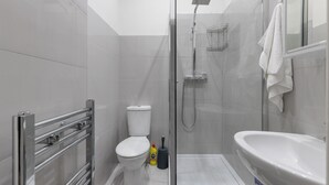 Moderni kylpyhuone, jossa on wc, suihku ja pesuallas.