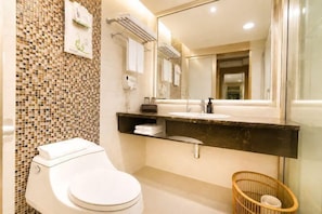 Un bagno moderno con una parete rivestita di mosaici, un water bianco, un mobile lavabo nero e un cesto in vimini.