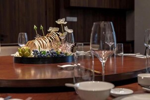 Una mesa de comedor dispuesta con un centro de mesa, copas de vino y vajilla blanca.
